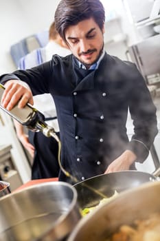 young adult chef in the restaurant kitchen while cooking at the herd preparation