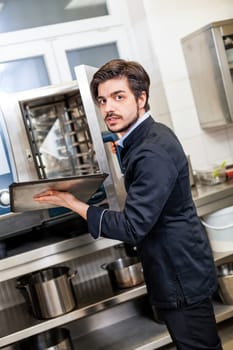 young adult chef in the restaurant kitchen while cooking at the herd preparation