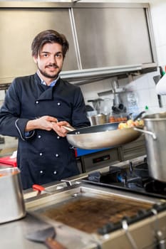 young adult chef in the restaurant kitchen while cooking at the herd preparation