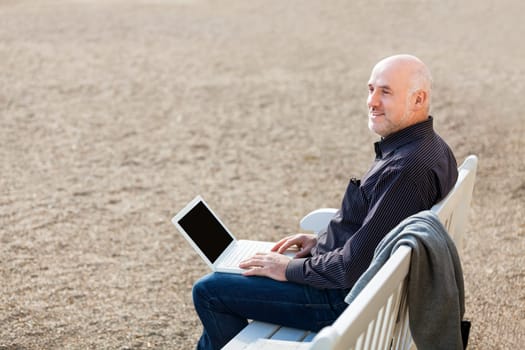 Businessman senior with notebook laptop during lunch break in summer outdoors