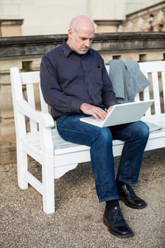 Businessman senior with notebook laptop during lunch break in summer outdoors