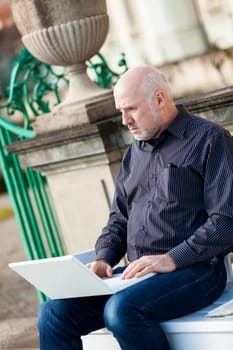 Businessman senior with notebook laptop during lunch break in summer outdoors