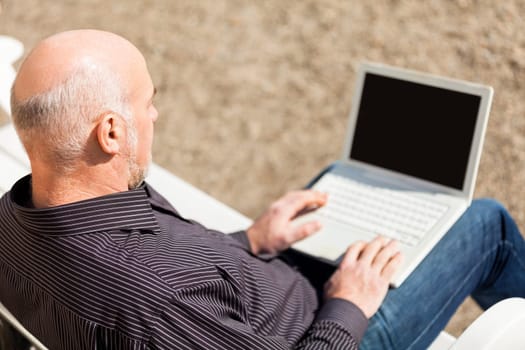 Businessman senior with notebook laptop during lunch break in summer outdoors