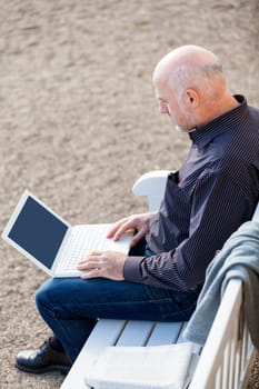 Businessman senior with notebook laptop during lunch break in summer outdoors