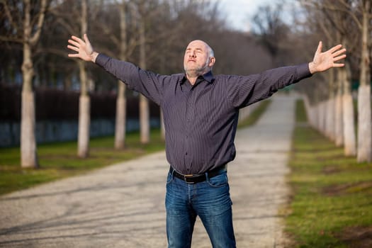 Man middle Altres pensioner with outstretched arms enjoys the fresh air