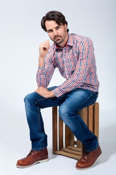 Young man with beard and dark hair with jeans and carated shirt