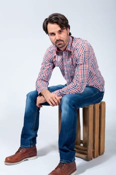 Young man with beard and dark hair with jeans and carated shirt