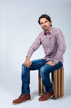 Young man with beard and dark hair with jeans and carated shirt