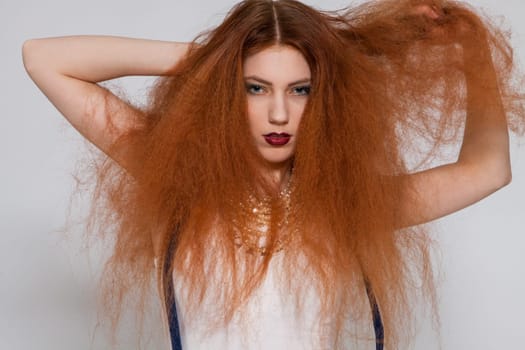 Young attractive pretty woman with long red hair and ripped hairstyle in portrait
