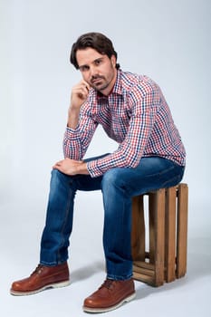 Young man with beard and dark hair with jeans and carated shirt