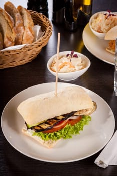 Vegetarian vegan hamburger with aubergine tomato and salad in a ciabatta bun
