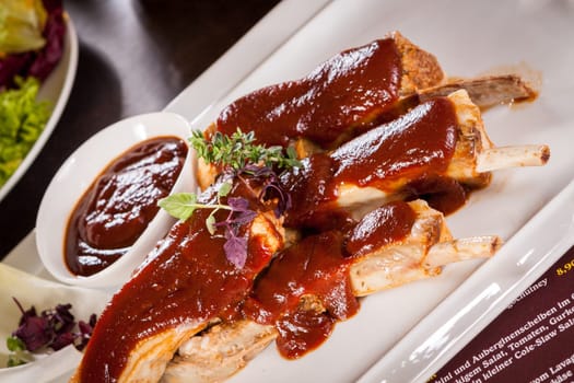 Grilled pork ribs Spareribs with barbecue sauce marinade and herb salad on a plate