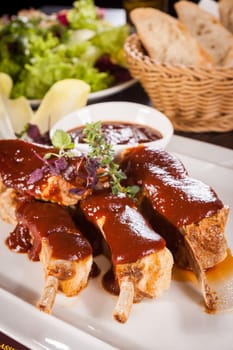 Grilled pork ribs Spareribs with barbecue sauce marinade and herb salad on a plate