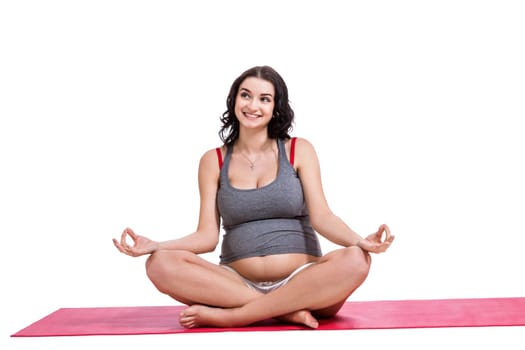 Attractive pregnant young woman makes yoga isolated against white background