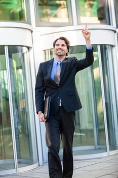 Attractive young businessman cheering in front of a business building in the summer