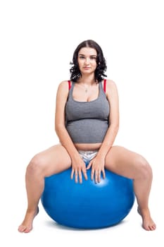 Attractive pregnant woman on a blue gymnastics ball to prepare for the brew