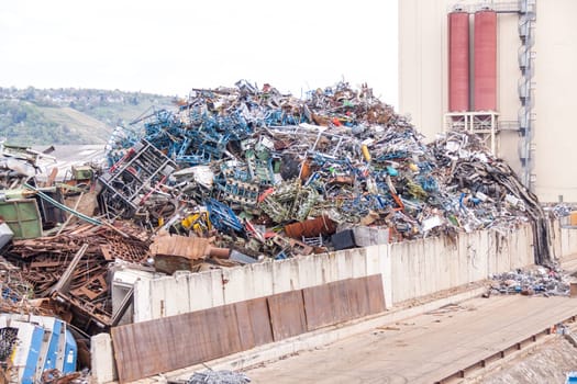 Truck crane with scrap metal loads a cargo ship at the dock with scrap