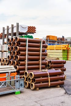 Different pipes for industry stacked in one warehouse in the open air
