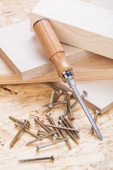 Close-up of a cross screwdriver with screws in wood while DIY in a workshop