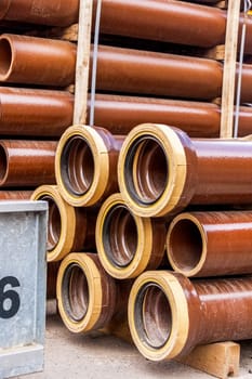 Different pipes for industry stacked in one warehouse in the open air