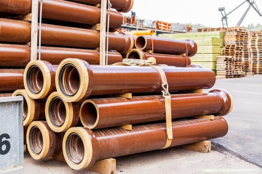 Different pipes for industry stacked in one warehouse in the open air
