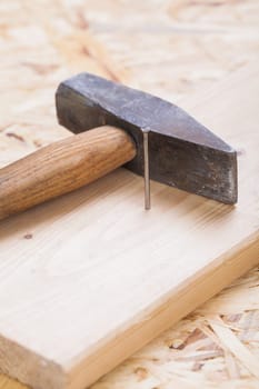 Hammer with nails on a wooden board in a workshop of a do-it-yourselfer