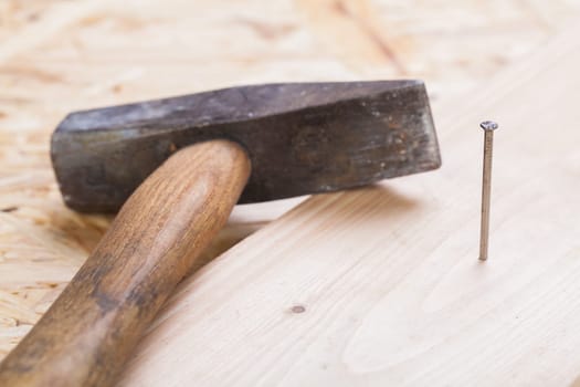 Hammer with nails on a wooden board in a workshop of a do-it-yourselfer