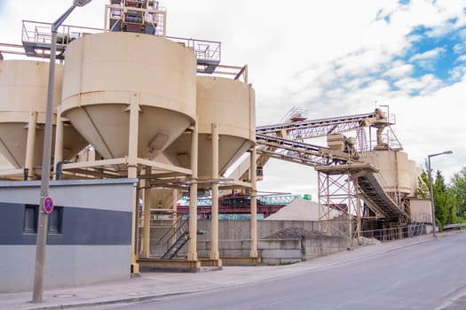 Large storage containers in a gravel plant for outdoor concrete production under a blue sky