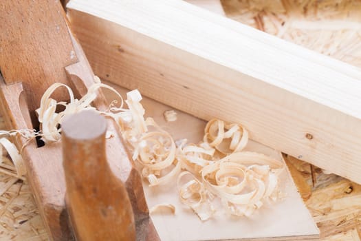 Planing with wood chips in a carpentry shop during woodworking in close-up detail