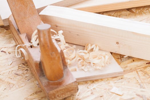 Planing with wood chips in a carpentry shop during woodworking in close-up detail