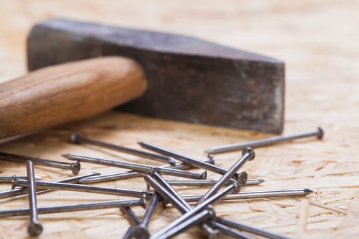 Hammer with nails on a wooden board in a workshop of a do-it-yourselfer