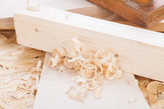 Planing with wood chips in a carpentry shop during woodworking in close-up detail