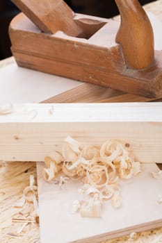 Planing with wood chips in a carpentry shop during woodworking in close-up detail