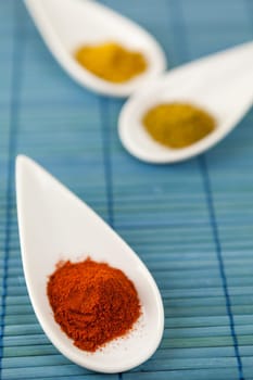 dried spices in porcelain bowls on a blue background