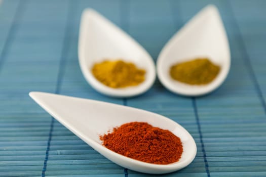 dried spices in porcelain bowls on a blue background