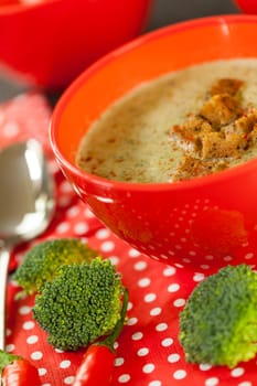 Soup bowl with broccoli soup with fresh pepper and chilli close-up on a wooden table