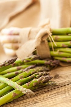 Fresh healthy green asparagus as a close-up on a wooden table in sunlight
