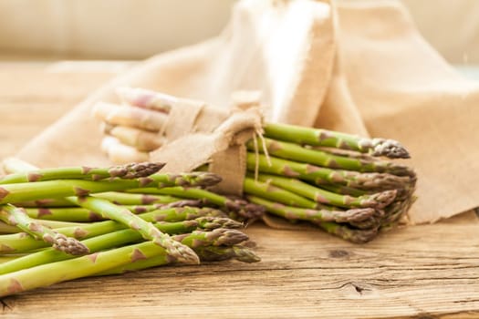 Fresh healthy green asparagus as a close-up on a wooden table in sunlight