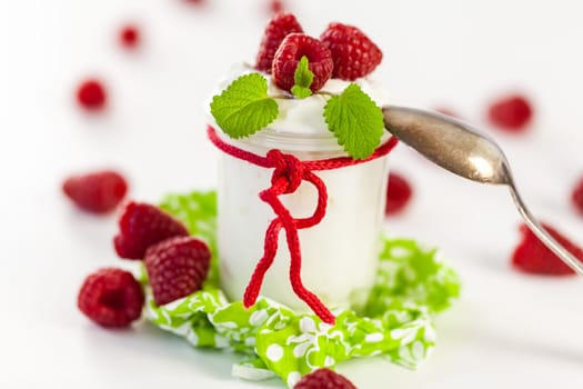 Fresh yoghurt with raspberries in a glass insulated on a white background
