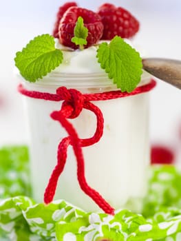 Fresh yoghurt with raspberries in a glass insulated on a white background