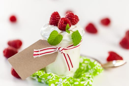 Fresh yoghurt with raspberries in a glass insulated on a white background