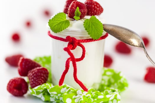Fresh yoghurt with raspberries in a glass insulated on a white background