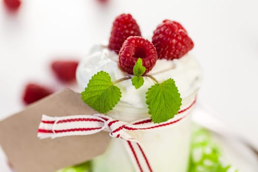 Fresh yoghurt with raspberries in a glass insulated on a white background