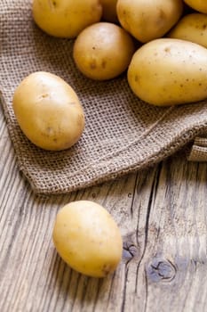 Fresh new potatoes on a jute sack with a green background as a close-up