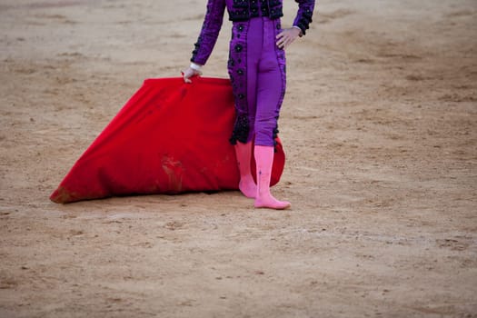 A barefoot bullfighter waits the bull with the capote during a bullfight