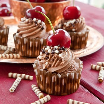 Chocolate cupcakes with buttercream and fresh cherries