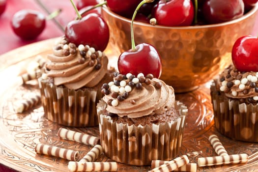 Chocolate cupcakes with buttercream and fresh cherries