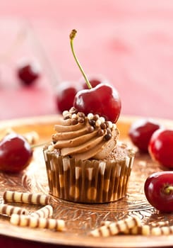 Chocolate cupcake with buttercream and fresh cherries