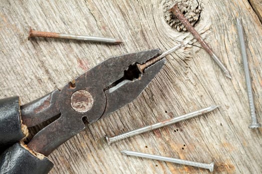 Old used pliers with nails on  wood table background