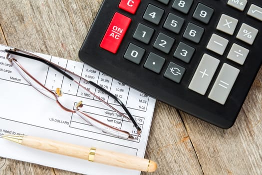 Invoice with balance due, calculator,pen and glasses